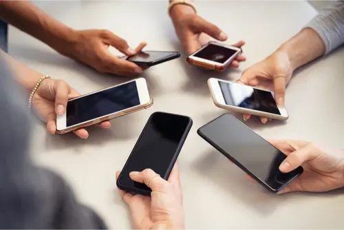 Gros plan sur des hommes et des filles mains en cercle en utilisant un smartphone. Vue en grand angle de plusieurs mains tenant un téléphone portable avec écran vide. Groupe d'amis multiculturels utilisant un smartphone ensemble.